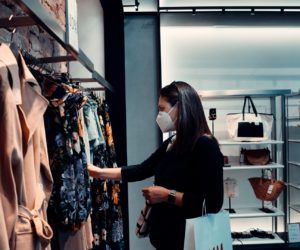 mujer con mascarilla de compras en tienda de ropa